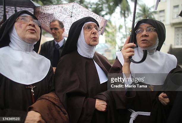 Nuns from the Nossa Senhora dos Anjos monastery wait in line in the rain to attend Pope Francis' visit to the Hospital de Sao Francisco de Assis on...