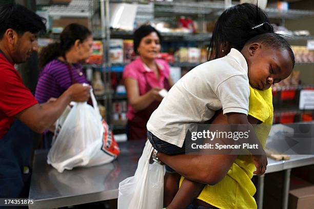 Jaden Painegua rests on his mother's shoulder at the West Side Campaign Against Hunger food bank on July 24, 2013 in New York City. The food bank...