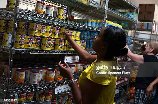 Client of the West Side Campaign Against Hunger food bank takes items from the shelf on July 24, 2013 in New York City. The food bank assists...