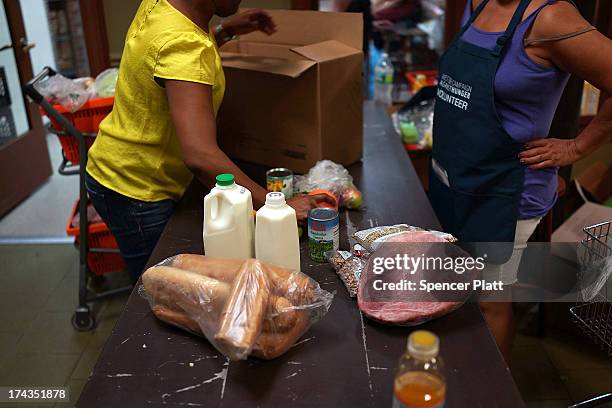 Client of the West Side Campaign Against Hunger food bank fills up a box with food on July 24, 2013 in New York City. The food bank assists thousands...