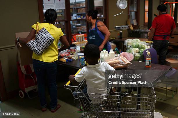 Jaden Painegua watches as his mother at the West Side Campaign Against Hunger food pantry as his mother shops for food on July 24, 2013 in New York...