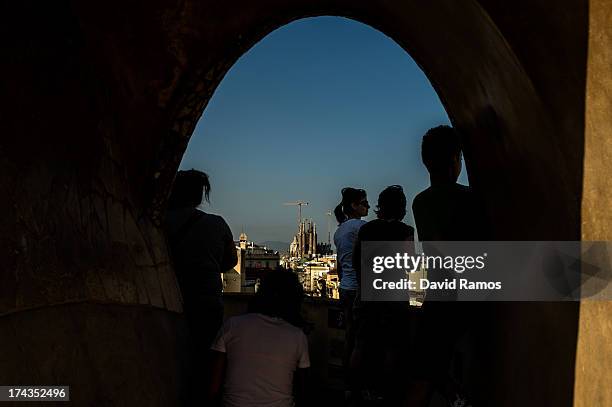 People look on from the roof of the building 'La Pedrera' or 'Casa Mila' of Antoni Gaudi with La Sagrada Familia on the background on July 24, 2013...