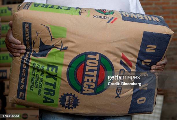 Worker stacks bags of Cemex SAB's Tolteca brand cement at a distribution center in Barrientos in the state of Mexico on Wednesday, July 24, 2013....