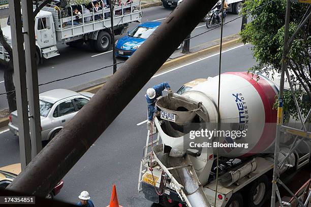 Worker washes a Cemex SAB truck after pouring concrete during construction of a building in Mexico City, Mexico. On Friday, July 19, 2013. Mexican...