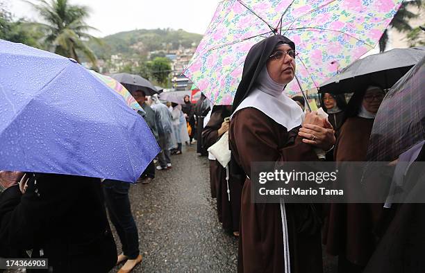 Nuns from the Nossa Senhora dos Anjos monastery wait in line in the rain to attend Pope Francis' visit to the Hospital de Sao Francisco de Assis on...