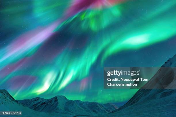 strong kp index aurora borealis (northern lights) exploding over the alaskan peaks near atigun pass along the dalton highway, located to the north of fairbanks, alaska, usa. - nordlicht stock-fotos und bilder