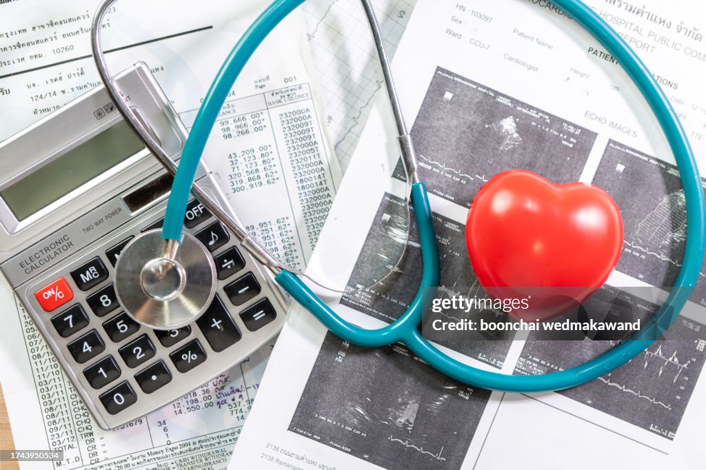 Cardiogram chart with medical stethoscope and small red heart on table closeup