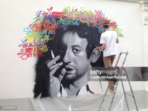 An anonymous street artist paints a mural of French singer-songwriter Serge Gainsbourg on a wall in the left bank area of Paris, France, 13th July...