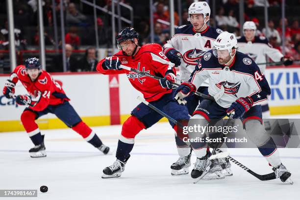 Evgeny Kuznetsov of the Washington Capitals battles Zach Werenski and Erik Gudbranson of the Columbus Blue Jackets for the puck during the second...