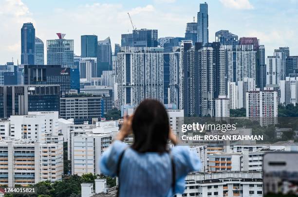 Woman takes pictures of the skyline of buildings from Mont Faber hill in Singapore on October 25, 2023.