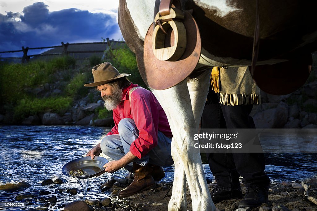 Characters: Gold Prospector pans in stream near mountain.