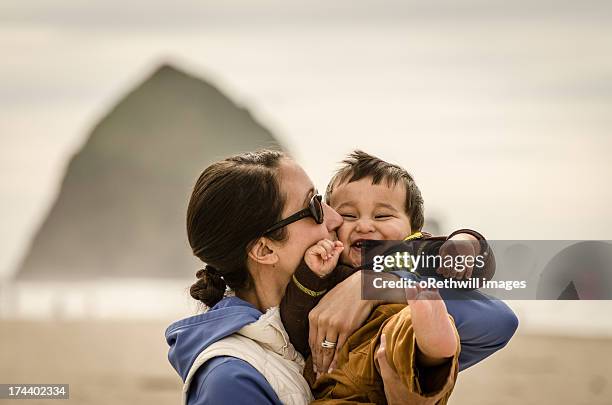 mother holding son at the beach - côte de l'oregon photos et images de collection