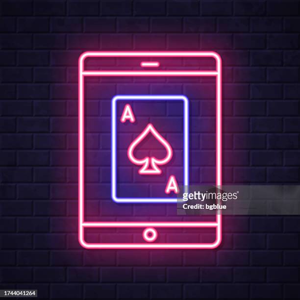 tablet pc with playing card. glowing neon icon on brick wall background - blackjack stock illustrations