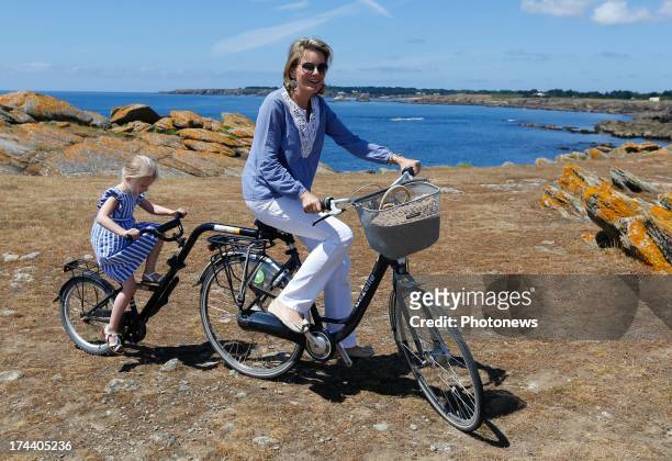 Queen Mathilde of Belgium rides on her bike with Princess Eleonore of Belgium during their holiday on l'Ile d'Yeu on July 24, 2013 in Yeu, France.