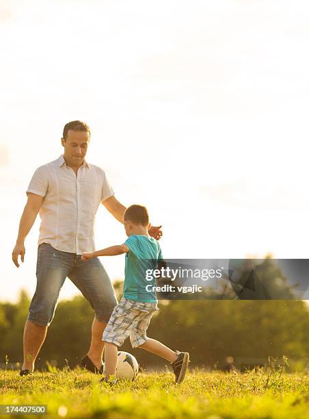 little boy playing soccer with father outdoors. - family time stock pictures, royalty-free photos & images