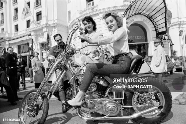 French actress Pauline Lafont rides a chopper motorcycle as her mother French actress Bernadette Lafont stands behind on March 14, 1980 during the...