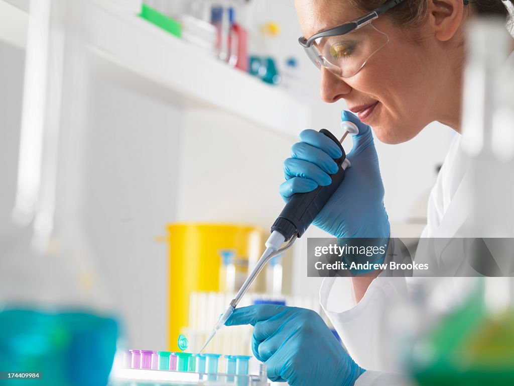 Female scientist pipetting DNA sample into vial in the laboratory