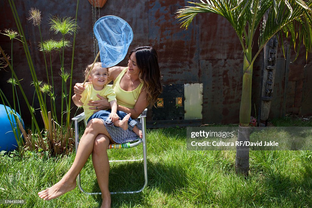 Mother and son sitting on chair in garden with fishing net