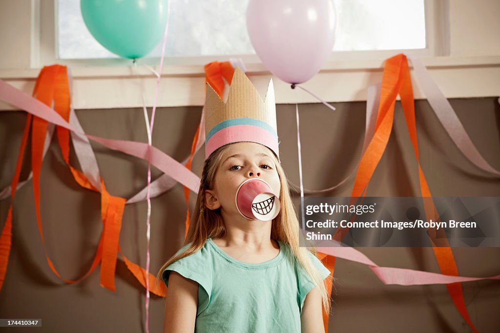 Child with paper cup over mouth