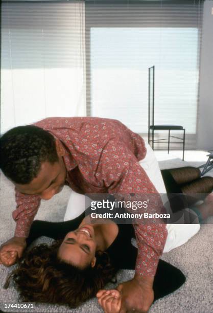 American actress Robin Givens smiles as her husband, heavyweight boxer Mike Tyson, pins her arms to the floor in their new home, Los Angeles,...