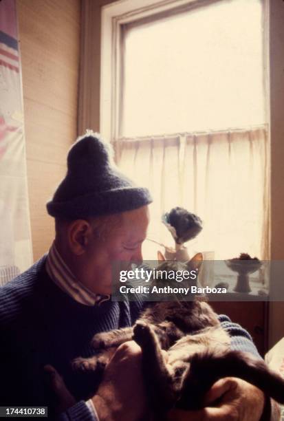 Portrait of American artist Romare Bearden as he sits at home and holds his cat in his arms, New York, 1972.