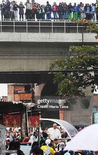 Pope Francis waves to the crowd while riding in the Popemobile as he tours the Varghina favela, or shantytown, on July 25, 2013 in Rio de Janeiro,...