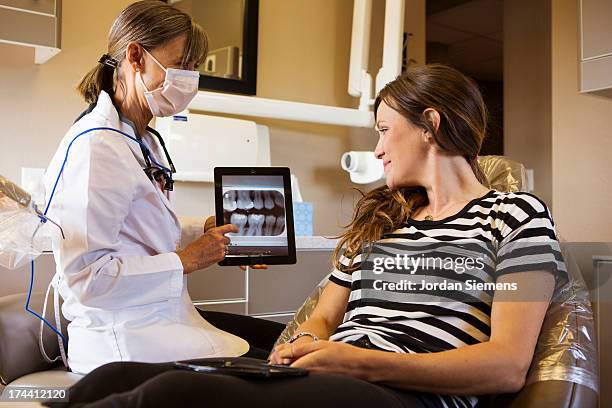 a digital tablet with a patients x-rays. - dental imaging stock pictures, royalty-free photos & images