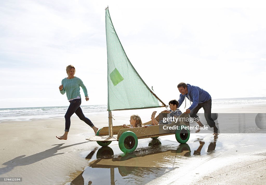 Family on beach in go kart with sail