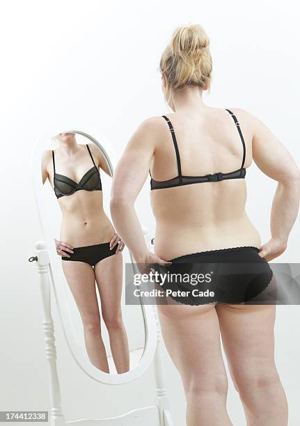 overweight girl looking at underweight reflection - frau in slip stock-fotos und bilder