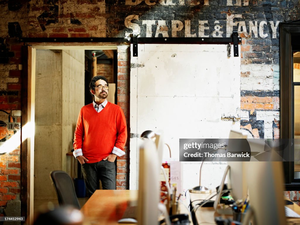 Designer leaning against door frame in office