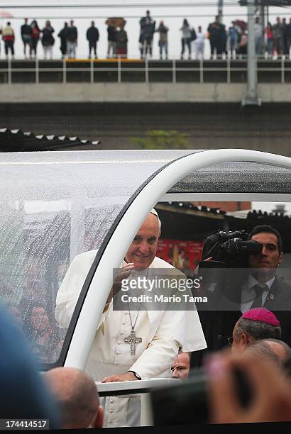Pope Francis waves to the crowd while riding in the Popemobile while touring the Varghina favela, or shantytown, on July 25, 2013 in Rio de Janeiro,...