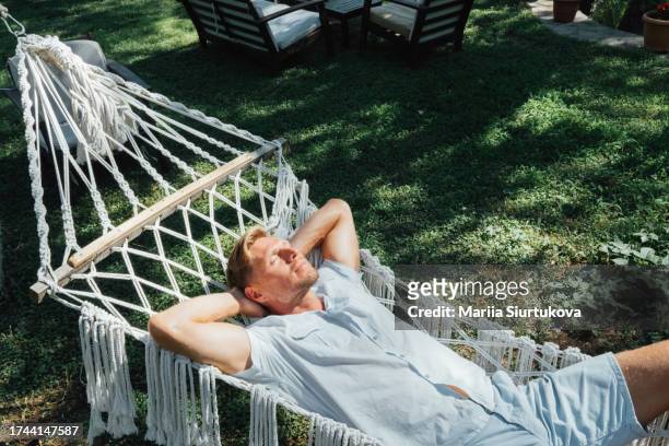 man relaxing in a hammock. - hammock stock pictures, royalty-free photos & images