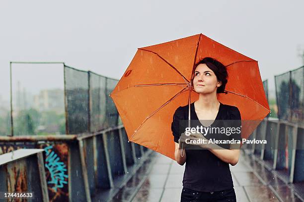 young woman with orange umbrella in the rain - chapéu - fotografias e filmes do acervo