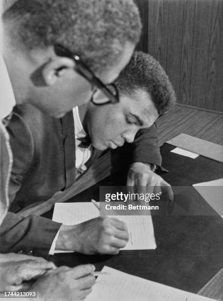 Heavyweight champion Muhammad Ali carefully crosses out the name Cassius Clay on the contract he is signing in Chicago, April 19th 1966. Ali changed...