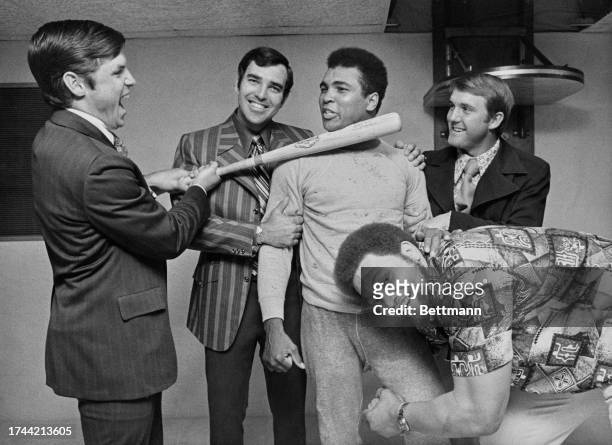 American boxer Muhammad Ali sharing a joke with New York Mets players Tom Seaver, Ed Kranepool and Tug McGraw, assisted by former football star Ernie...
