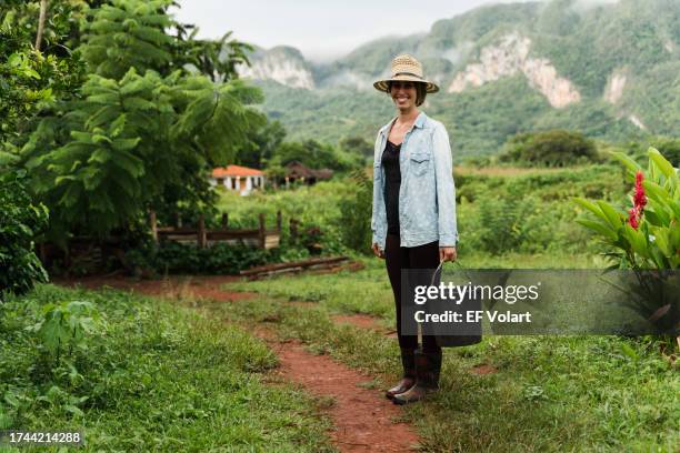 young woman farmer with harvesting bucket smiling in a tropical farm - costa rica coffee stock pictures, royalty-free photos & images