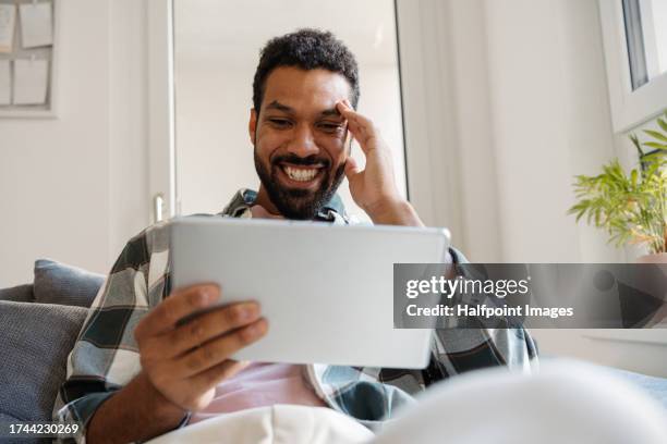 single man watching a tv series on a streaming platform alone. he sits solo on the couch and binge-watches the entire series. enjoying the single life as young man. - binge tv stockfoto's en -beelden