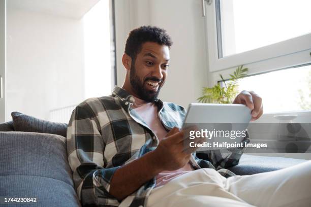 single man watching a tv series on a streaming platform alone. he sits solo on the couch and binge-watches the entire series. enjoying the single life as young man. - binge tv stockfoto's en -beelden