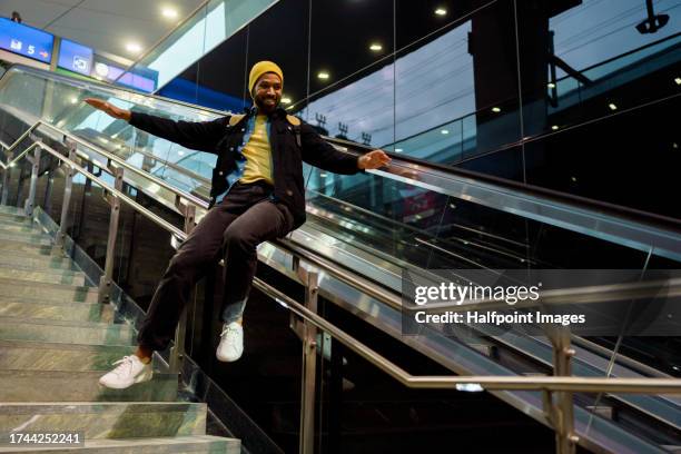 content single man slides down the stair railing. happy young guy commuting home from work by metro. single city life of a young university student. - garde corps photos et images de collection