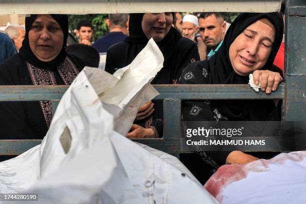 Graphic content / Women react while standing behind a truck carrying the bodies of Palestinian victims killed during Israeli bombardment, before...
