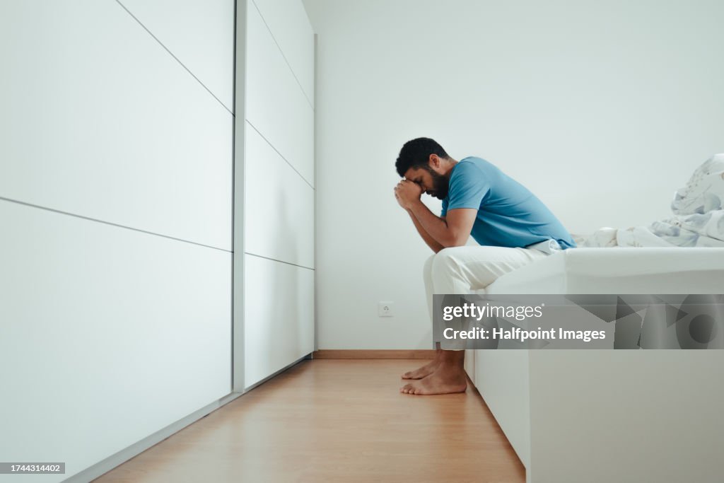 Single man waking up alone in his bed, feeling anxious and depressed in the morning. Loneliness and the need for connection with others, family.