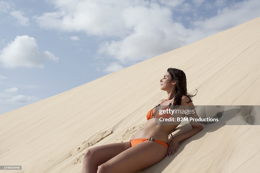 Young Woman Leaning On Sand In Desert