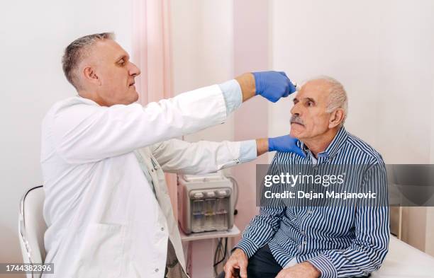 alter mann hat arztbesuch im krankenhaus und kontrolliert die temperatur - ordination stock-fotos und bilder