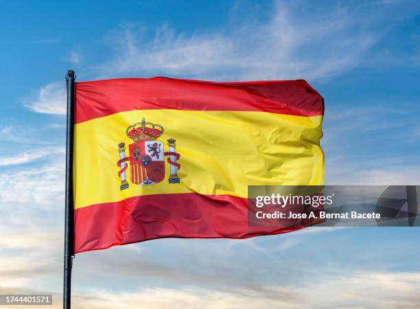 spain flag waving in the wind over a sunset sky. - spanish flag stock pictures, royalty-free photos & images