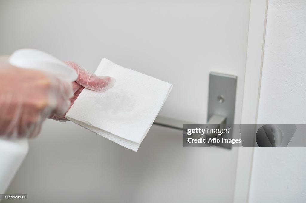 Japan man disinfecting door knob with alcohol