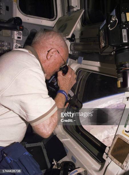 This 04 November photo released 06 November by NASA shows payload specialist Sen. John Glenn taking pictures of the Earth from on board the Discovery...