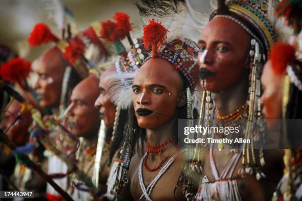 lineup of men with red faces and tribal beads - african tribal face painting stock-fotos und bilder