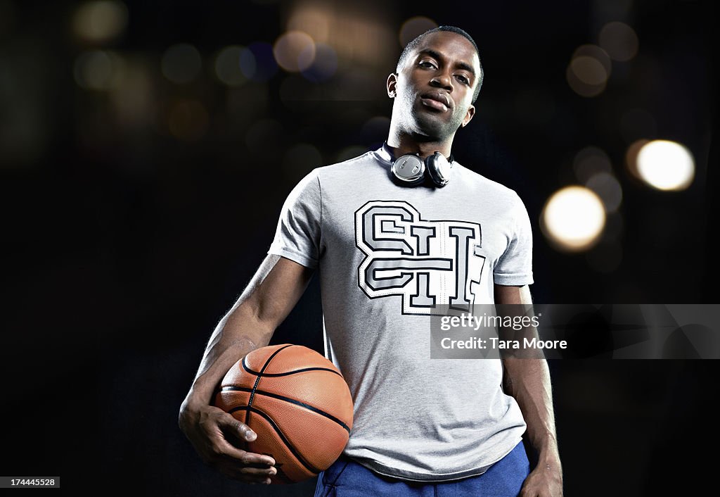 Portait of man holding basketball with headphones