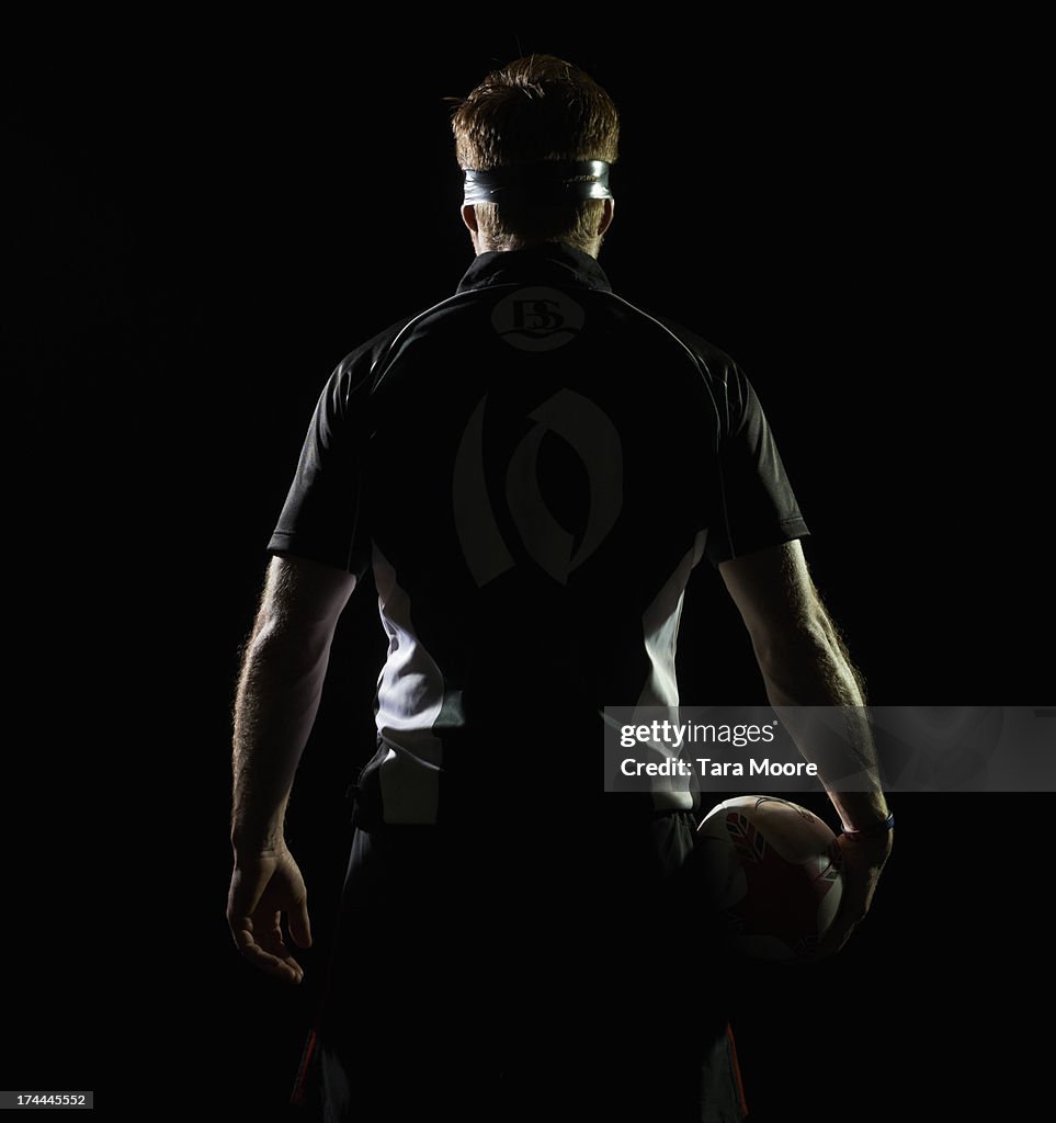 Back view of rugby player holding rugby ball