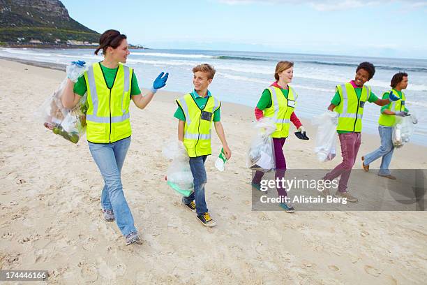 young people cleaning up a beach - volunteer beach photos et images de collection